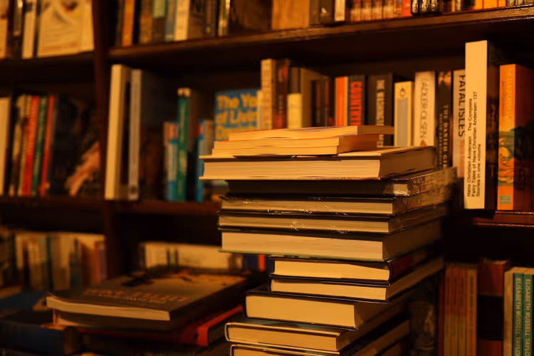 Libros sobre un escritorio junto a una estantería como imagen del espacio de trabajo de un escritor