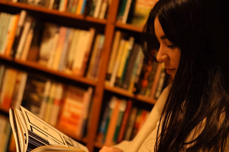 Woman choosing a book among library shelves