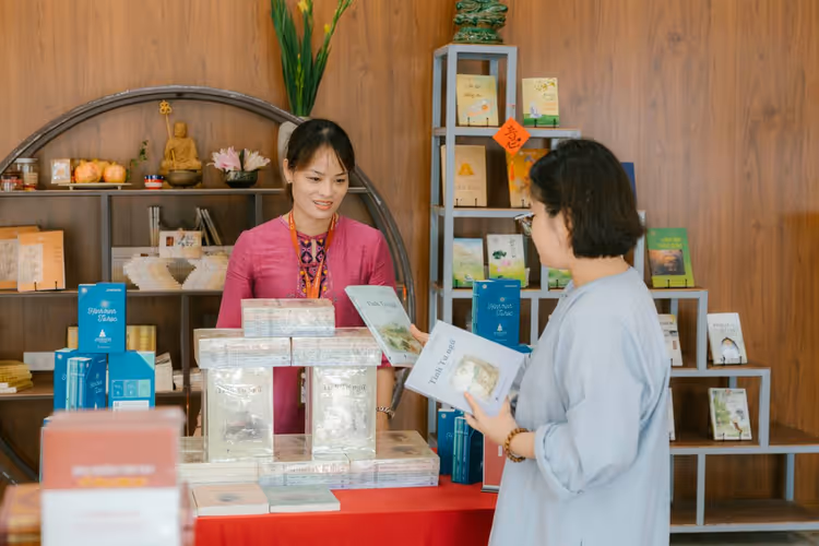 Two shoppers browse new books on a table in a store