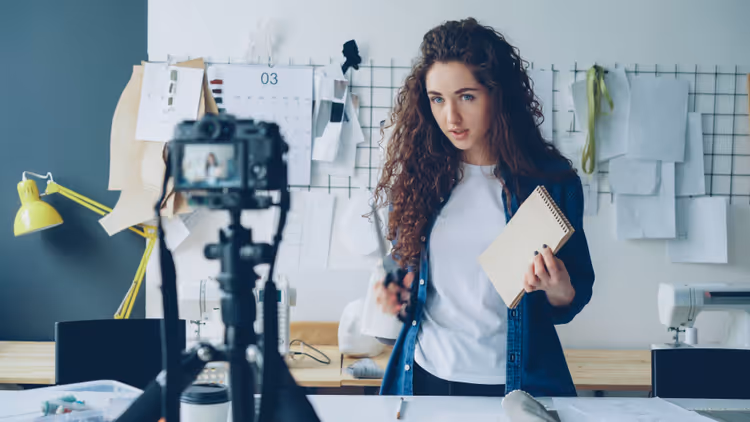 Content creator working at a desk with a camera and laptop in daylight