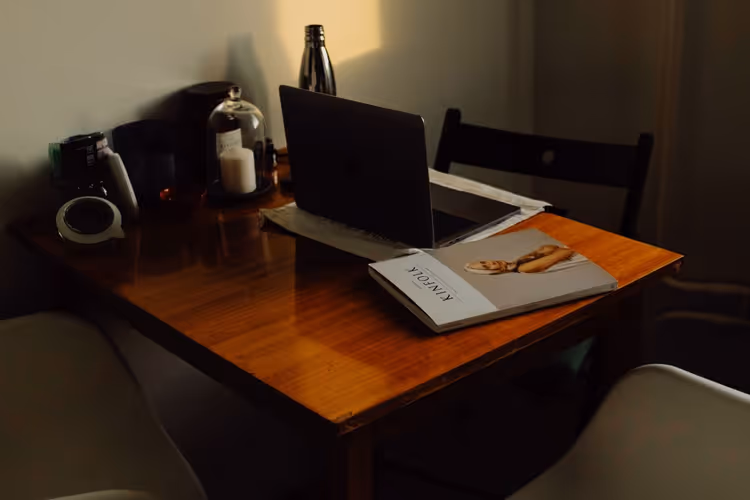 Writer's workspace: laptop, notebook, and a cup of coffee on a wooden desk
