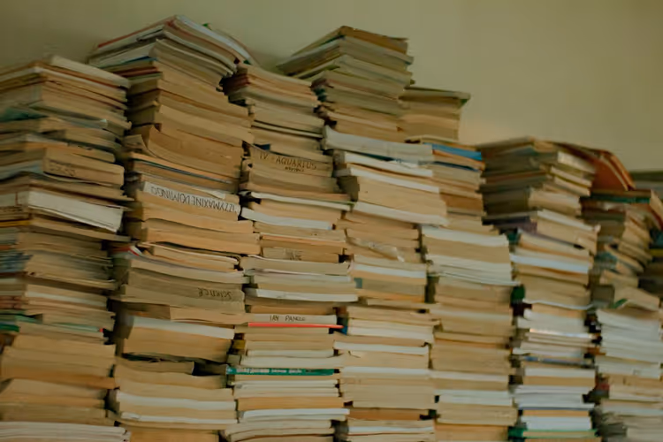 Pilas de libros antiguos en una biblioteca como imagen del catálogo acumulado de un autor