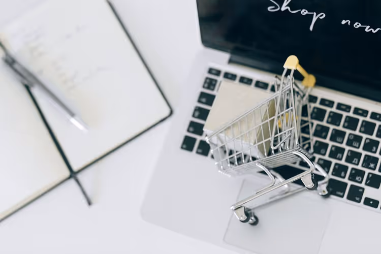 Miniature shopping cart on a laptop keyboard as a symbol of seasonal online shopping