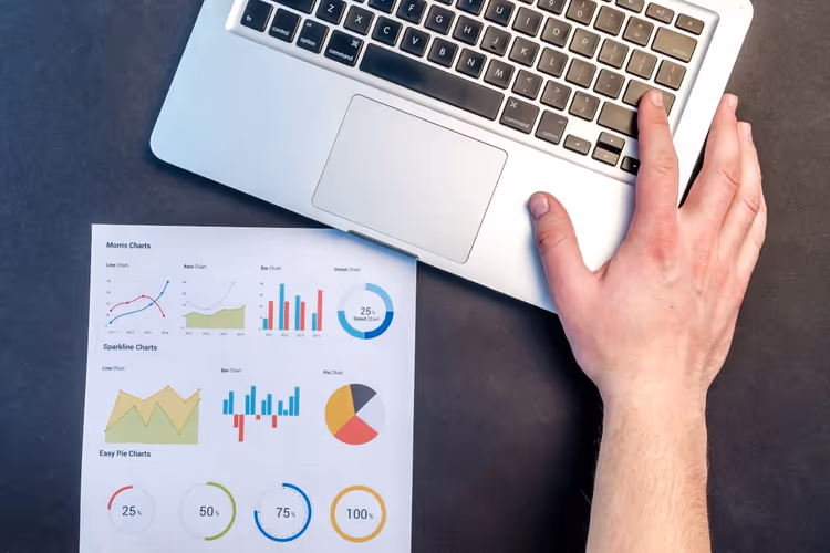 Desk with laptop and printed charts for analyzing results