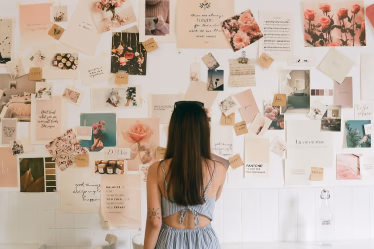 Woman reviewing a wall of images and cards to select visual references