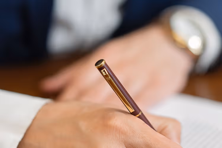 Close-up: hand signing a contract with a fountain pen