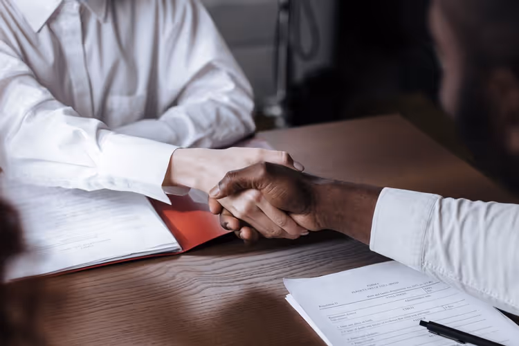 Handshake over documents as a symbol of agreement between author and editorial team